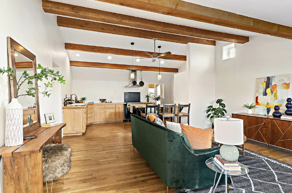 A living room with a green couch and wooden beams.