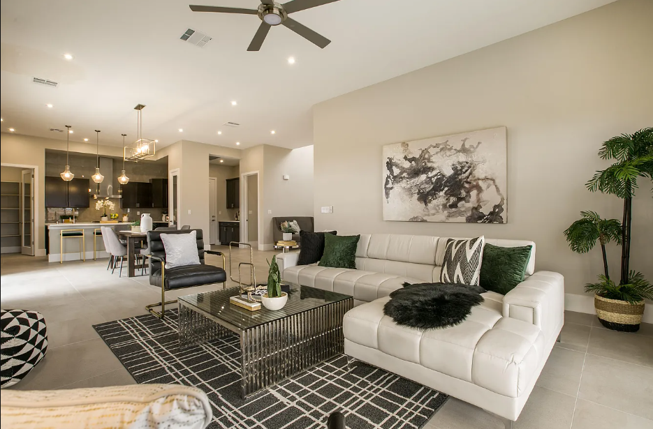 A living room with a couch , coffee table , chairs and a ceiling fan.