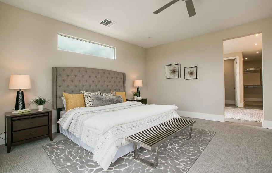 A bedroom with a bed , nightstands , lamps and a ceiling fan.