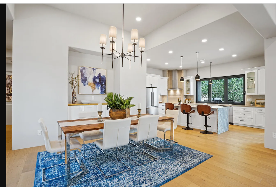 A dining room with a table and chairs and a blue rug.