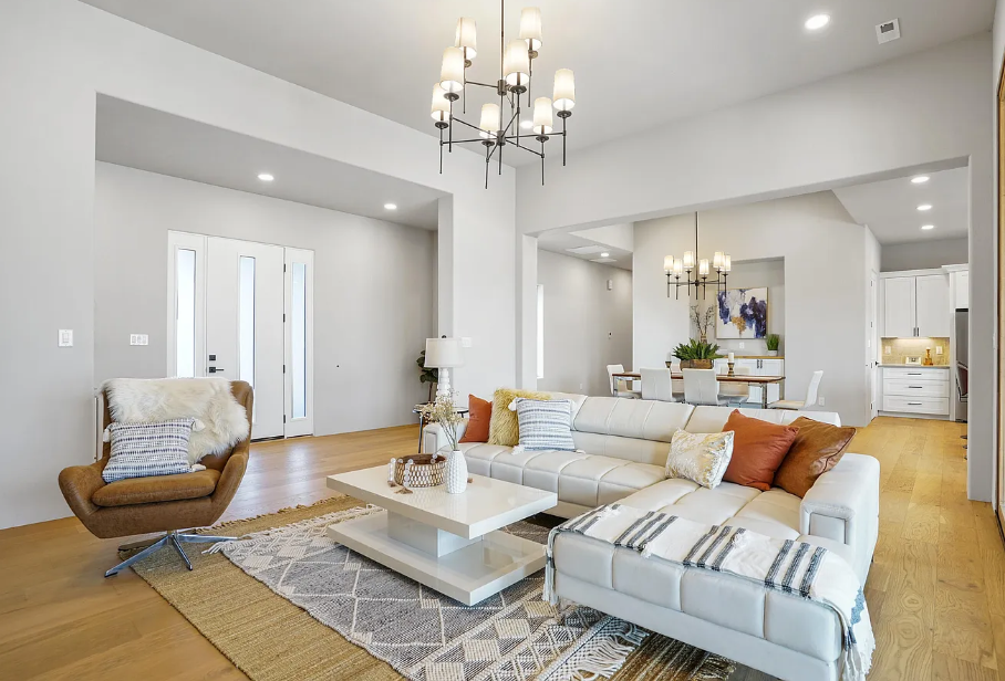 A living room with a couch , chair , coffee table and chandelier.