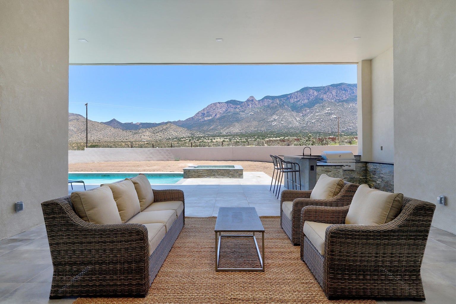 A living room with a couch , chairs and a table with a view of mountains.