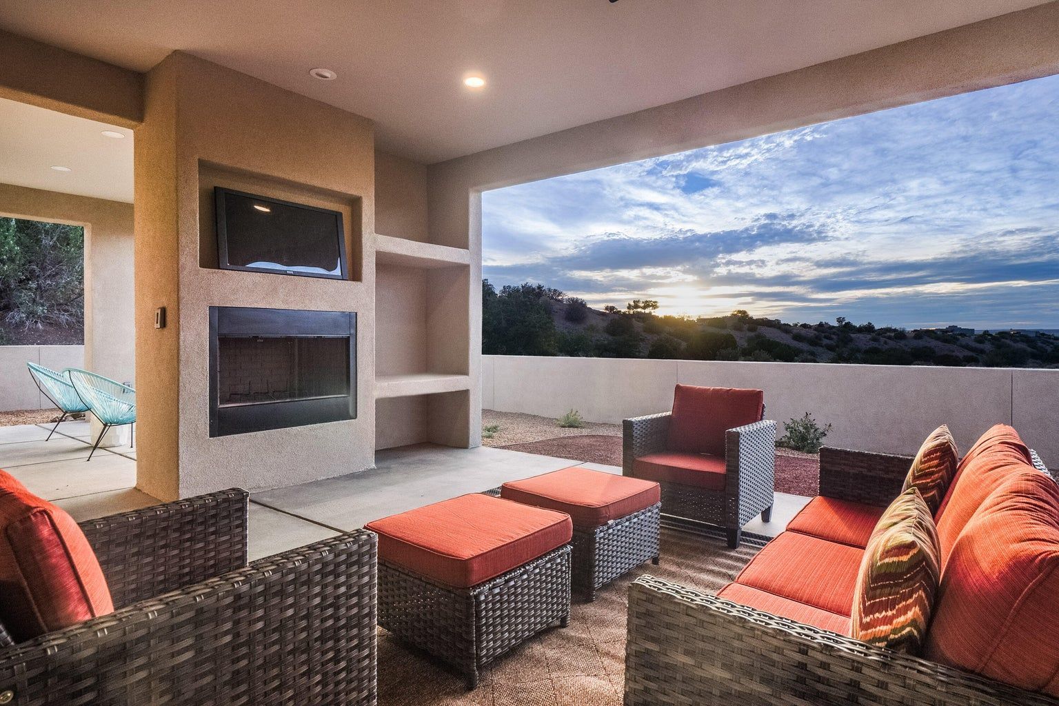 A patio with wicker furniture and a fireplace.