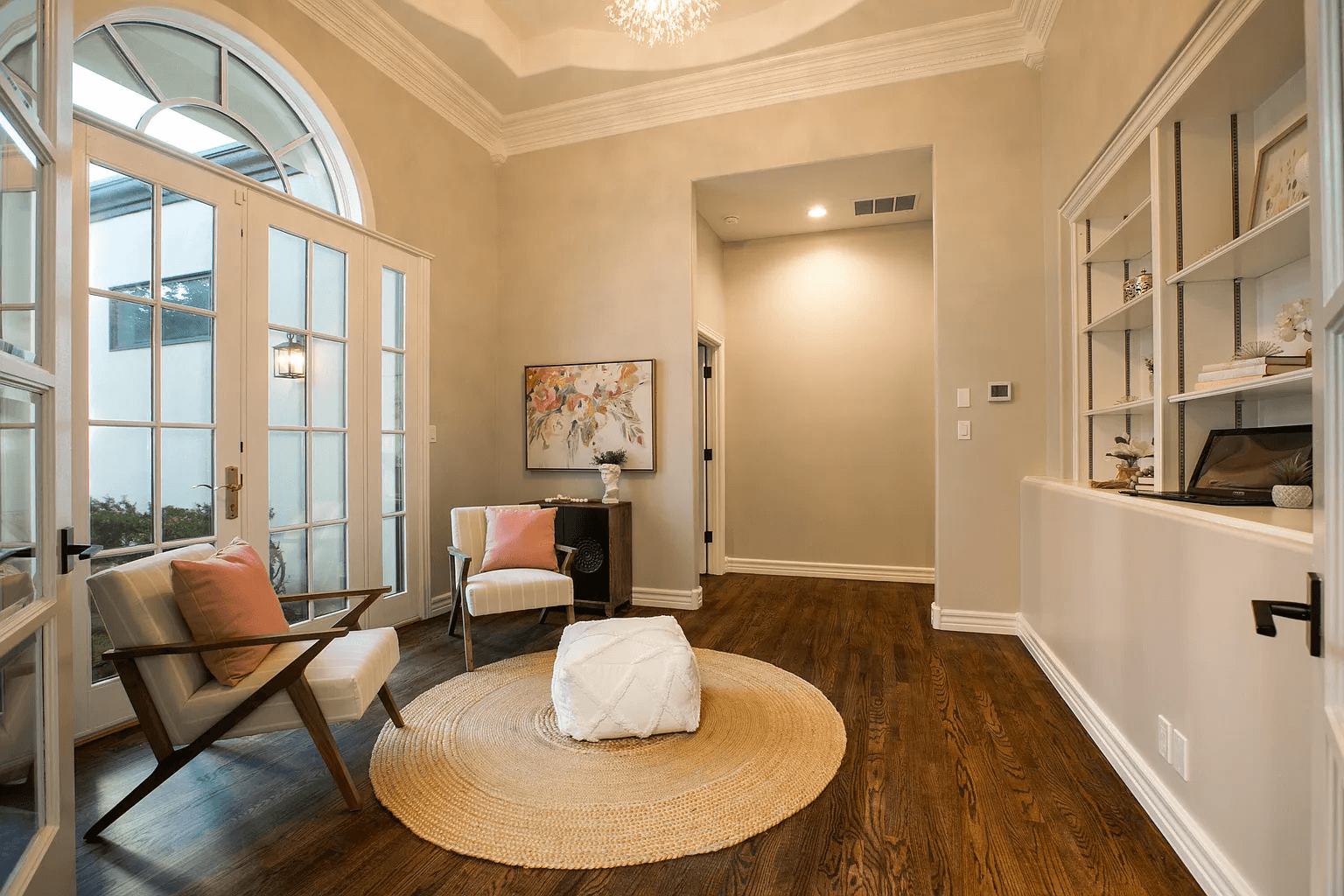 A living room with hardwood floors , chairs , ottomans and a rug.