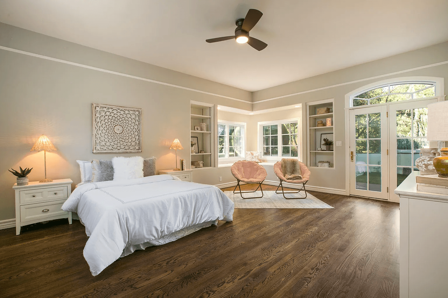 A bedroom with a bed , chairs and a ceiling fan.