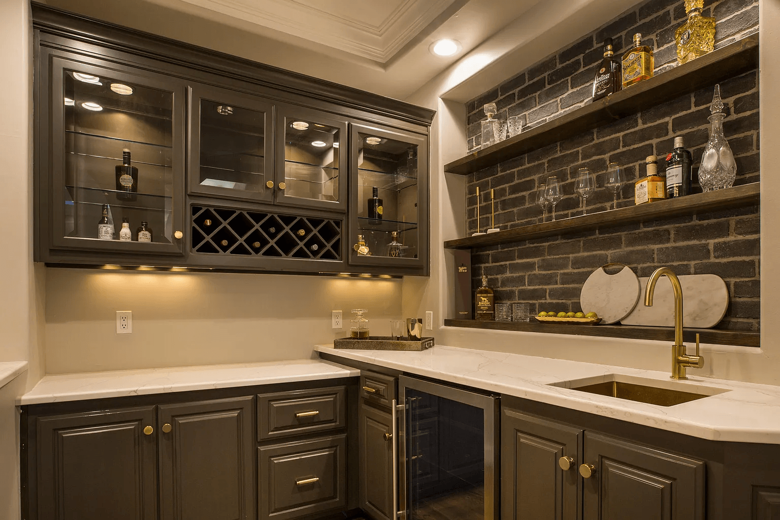 A kitchen with a sink , a refrigerator , a wine rack , and a brick wall.