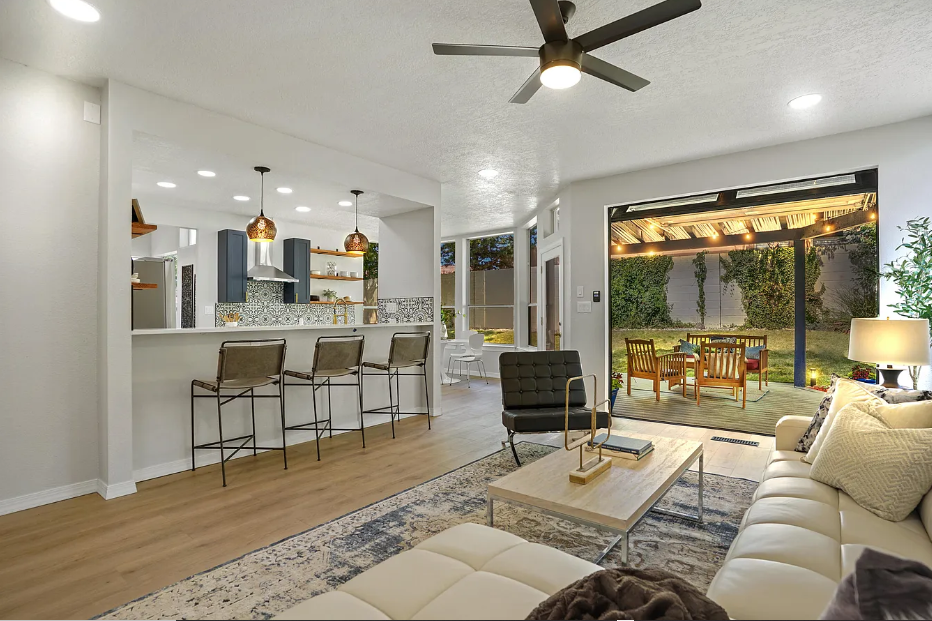 A living room with a couch , table , chairs and a ceiling fan.