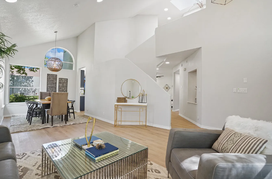 A living room with a couch , chair , coffee table and stairs leading to the dining room.