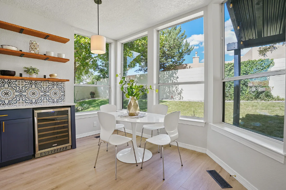 A dining room with a table and chairs and a wine cooler.
