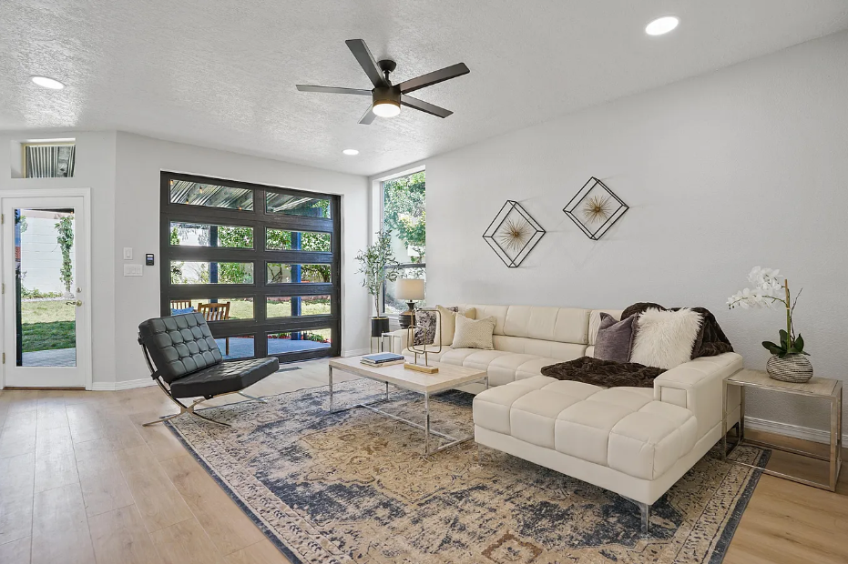 A living room with a couch , chair , coffee table and ceiling fan.