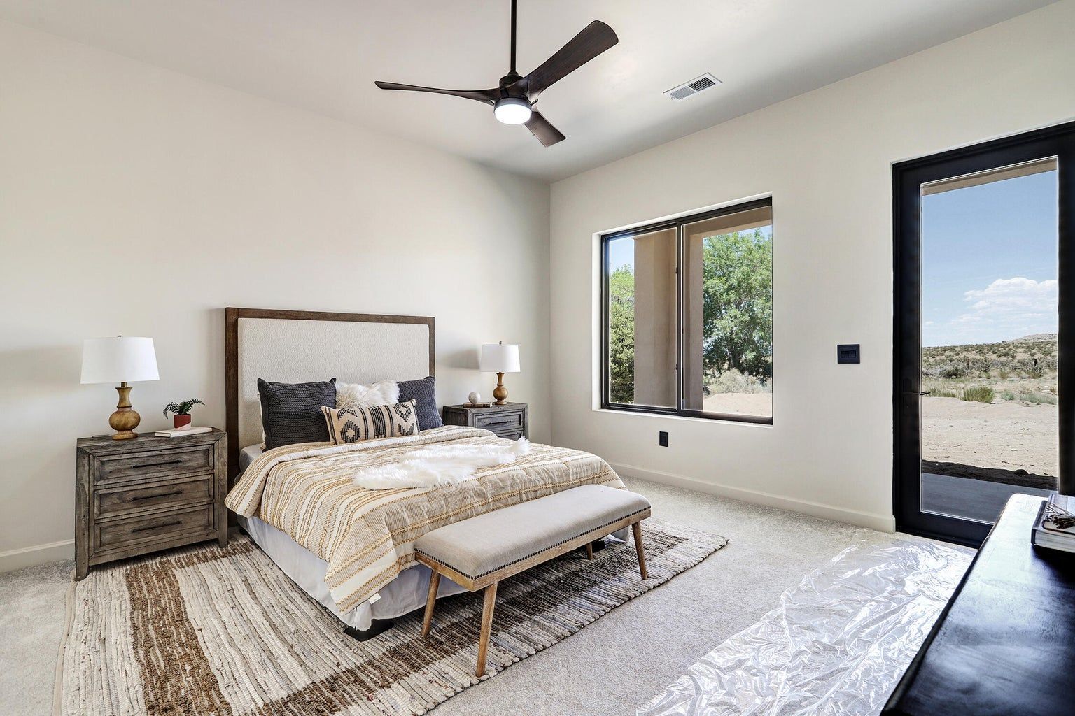 A bedroom with a bed , nightstand , ceiling fan and sliding glass doors.