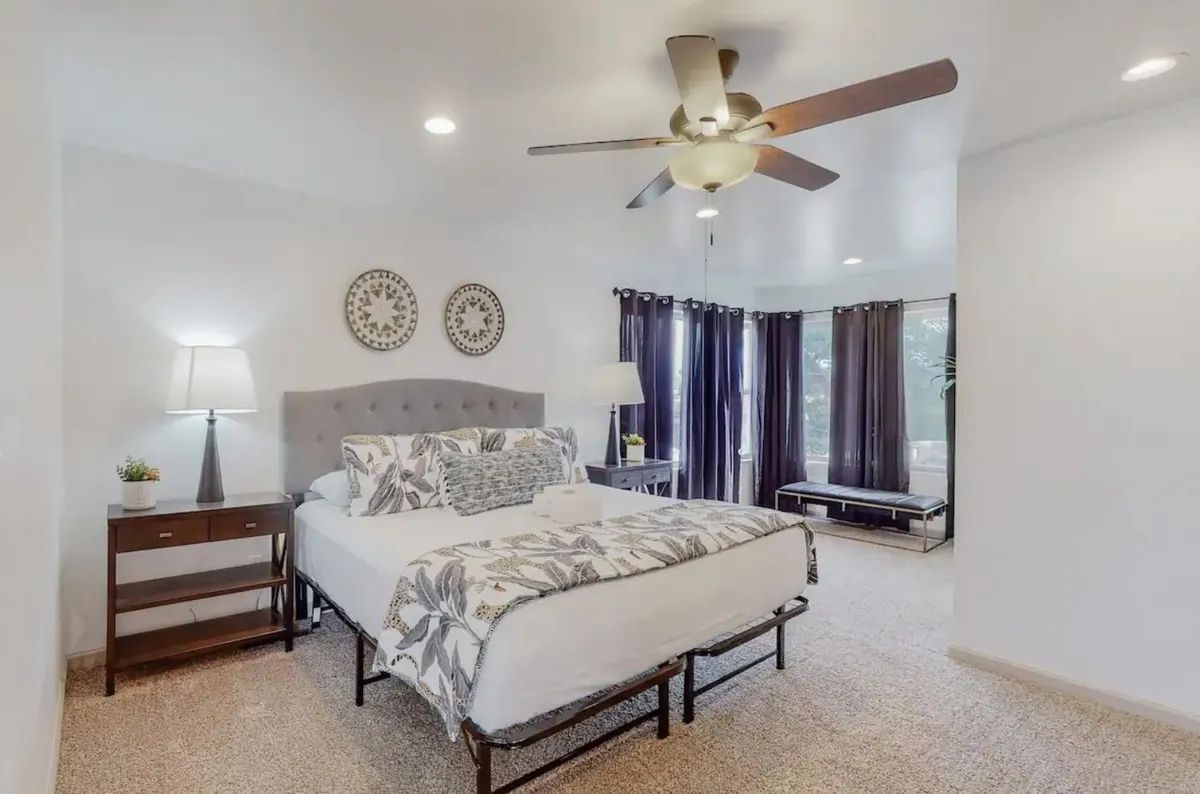A bedroom with a king size bed and a ceiling fan.