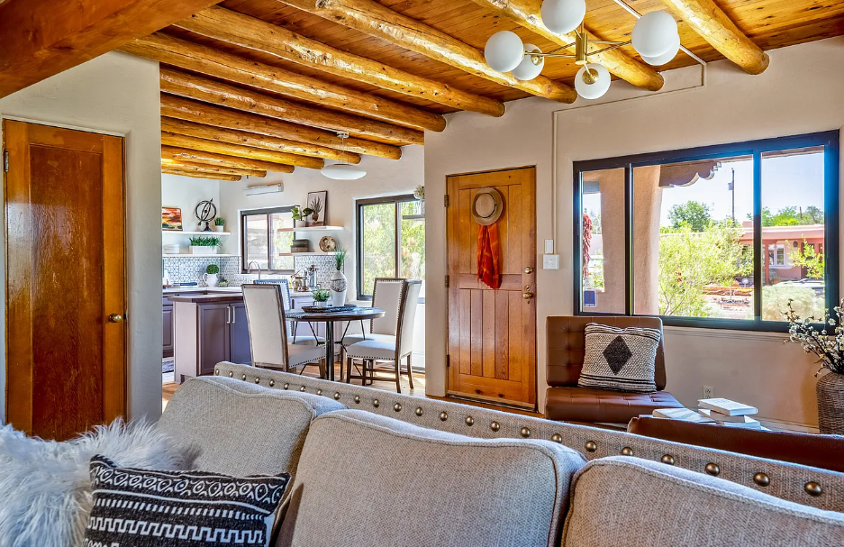 A living room with a couch , table , chairs and a wooden ceiling.