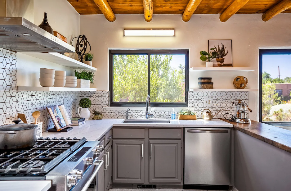 A kitchen with stainless steel appliances , gray cabinets , a stove and a sink.