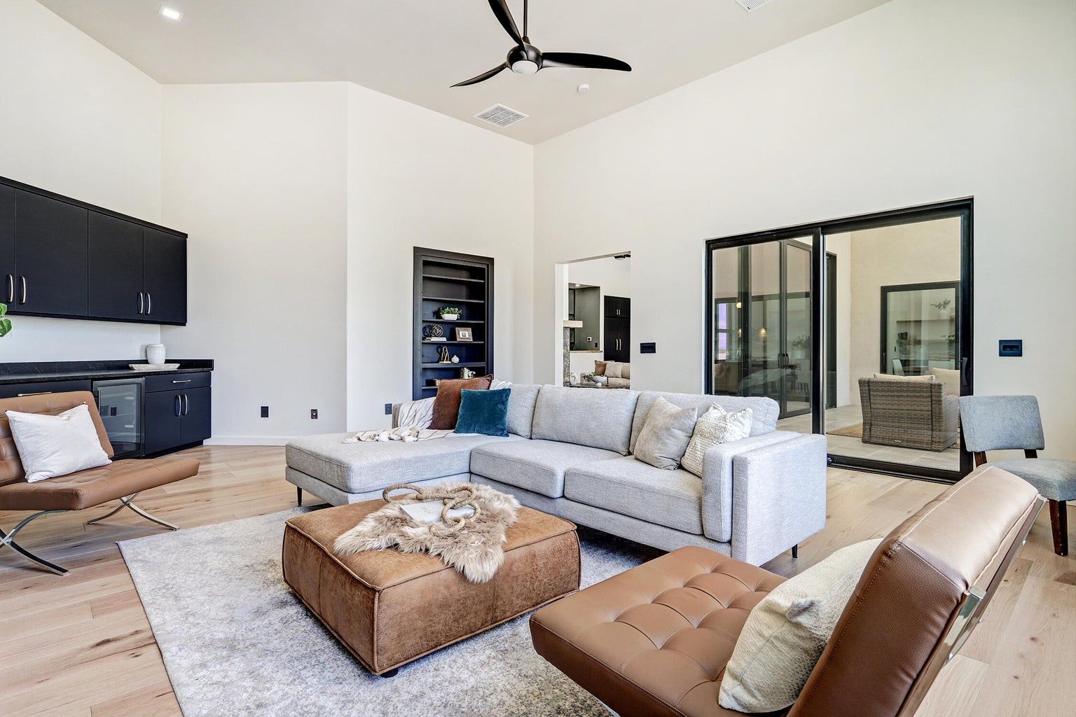 A living room with a couch , chairs , ottoman and ceiling fan.