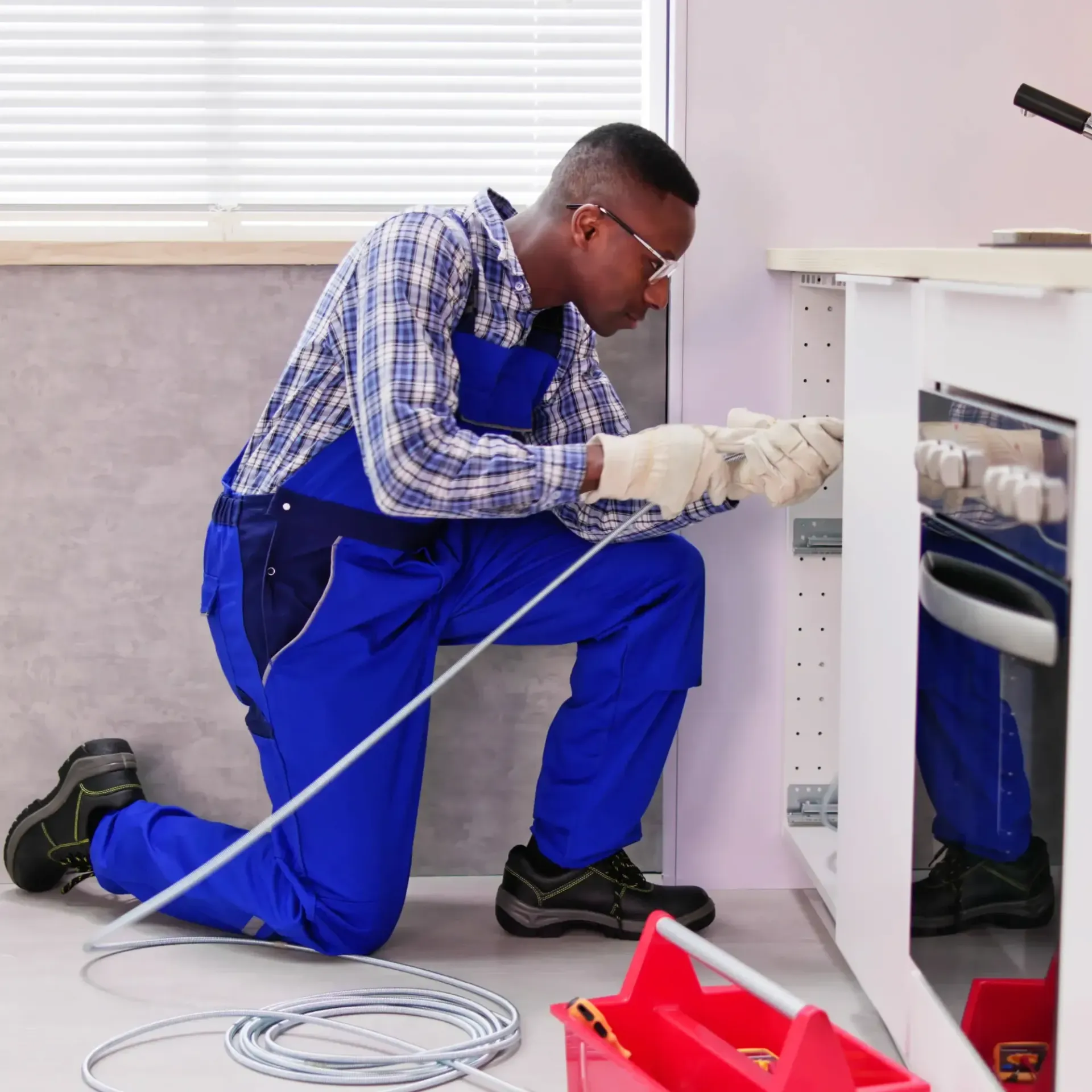 Pipex Plumbing - A man in blue overalls is working on a stove