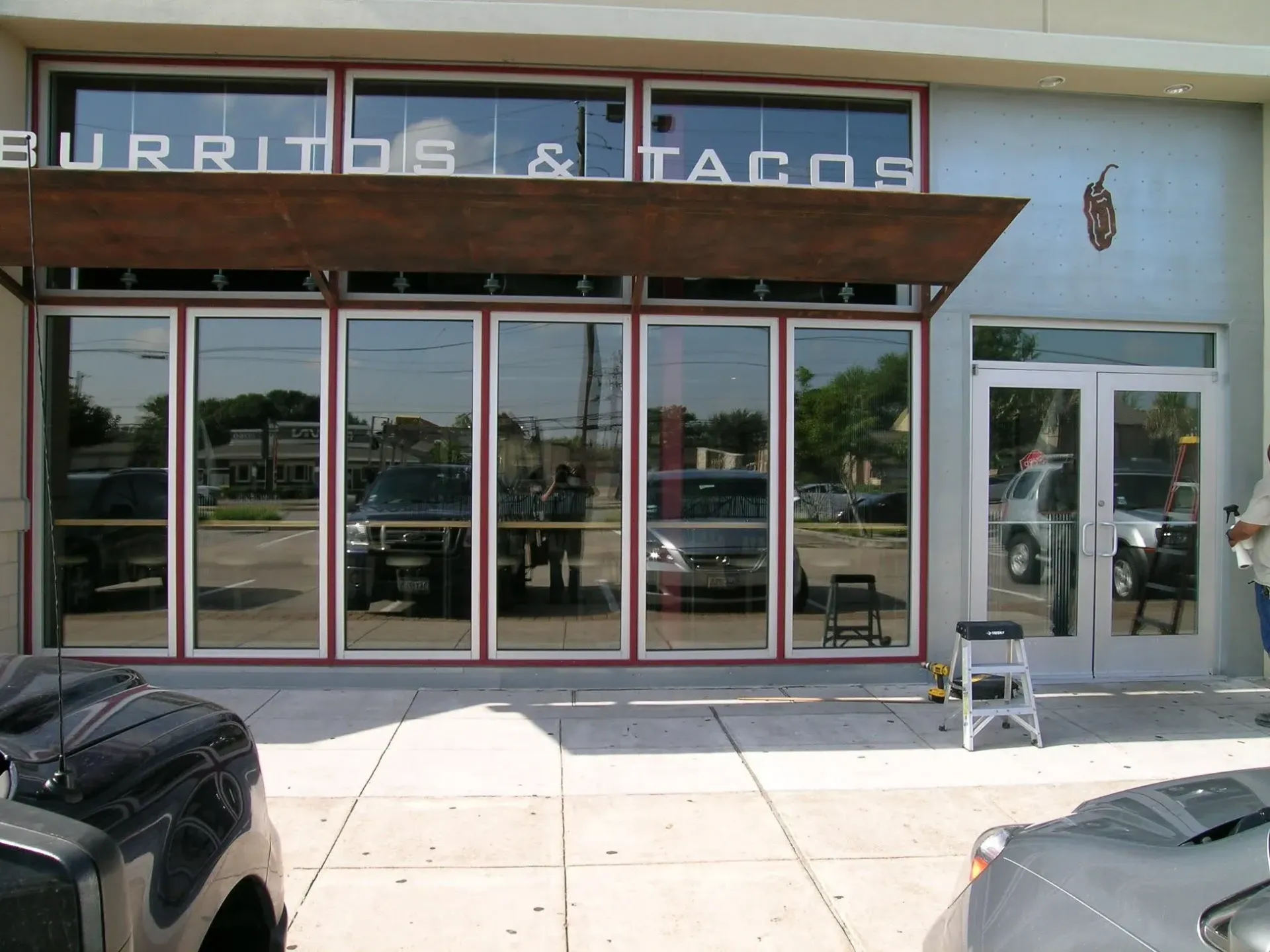Storefront with glass windows and a sign reading “MURIDOS & TAOS,” viewed from the sidewalk.