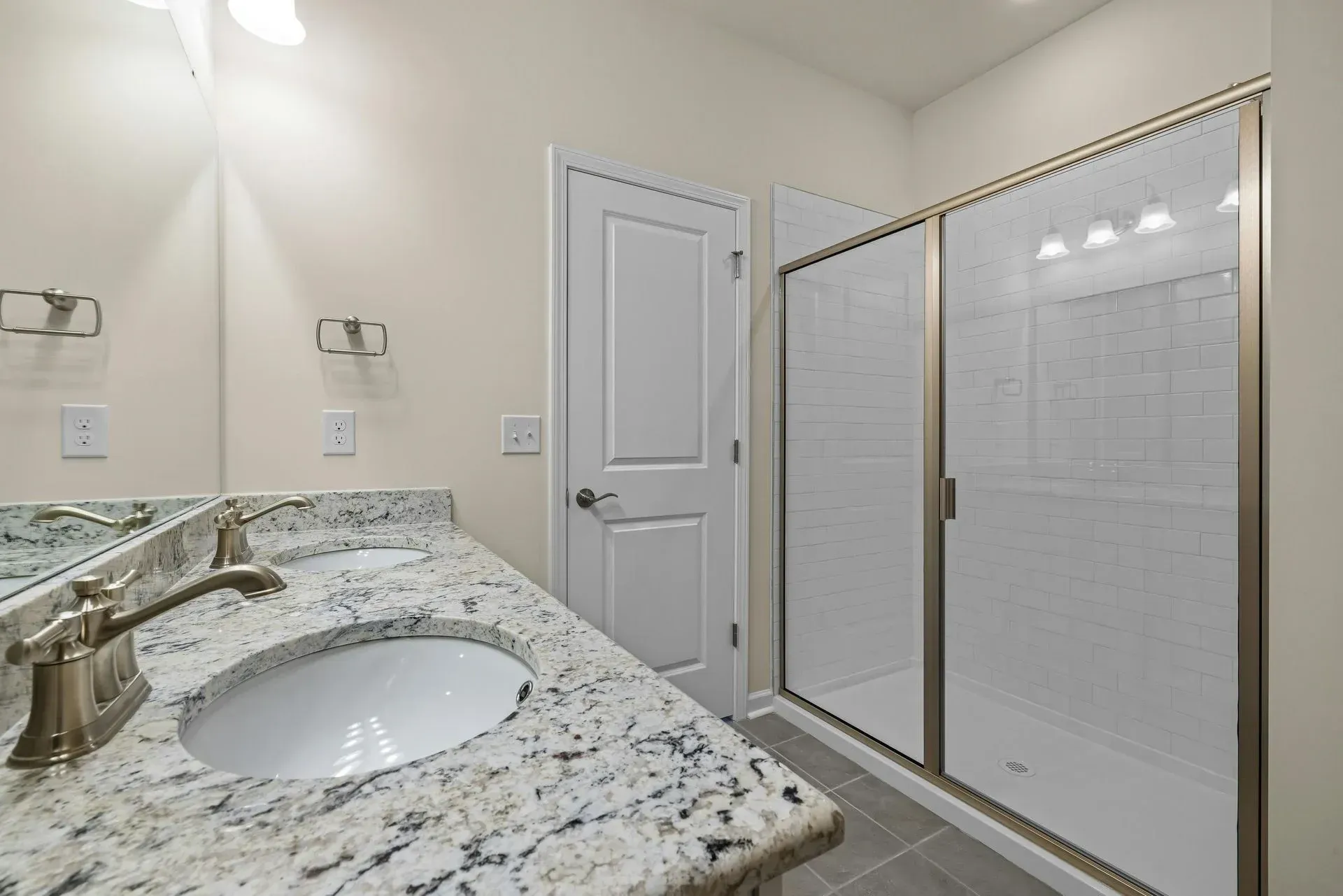 Bright bathroom with granite vanity, oval sink, and glass-enclosed shower.