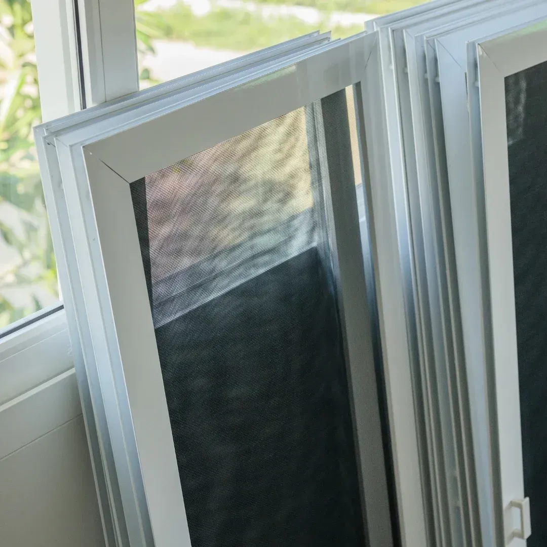 White window screen panels leaning open beside a sunlit window.