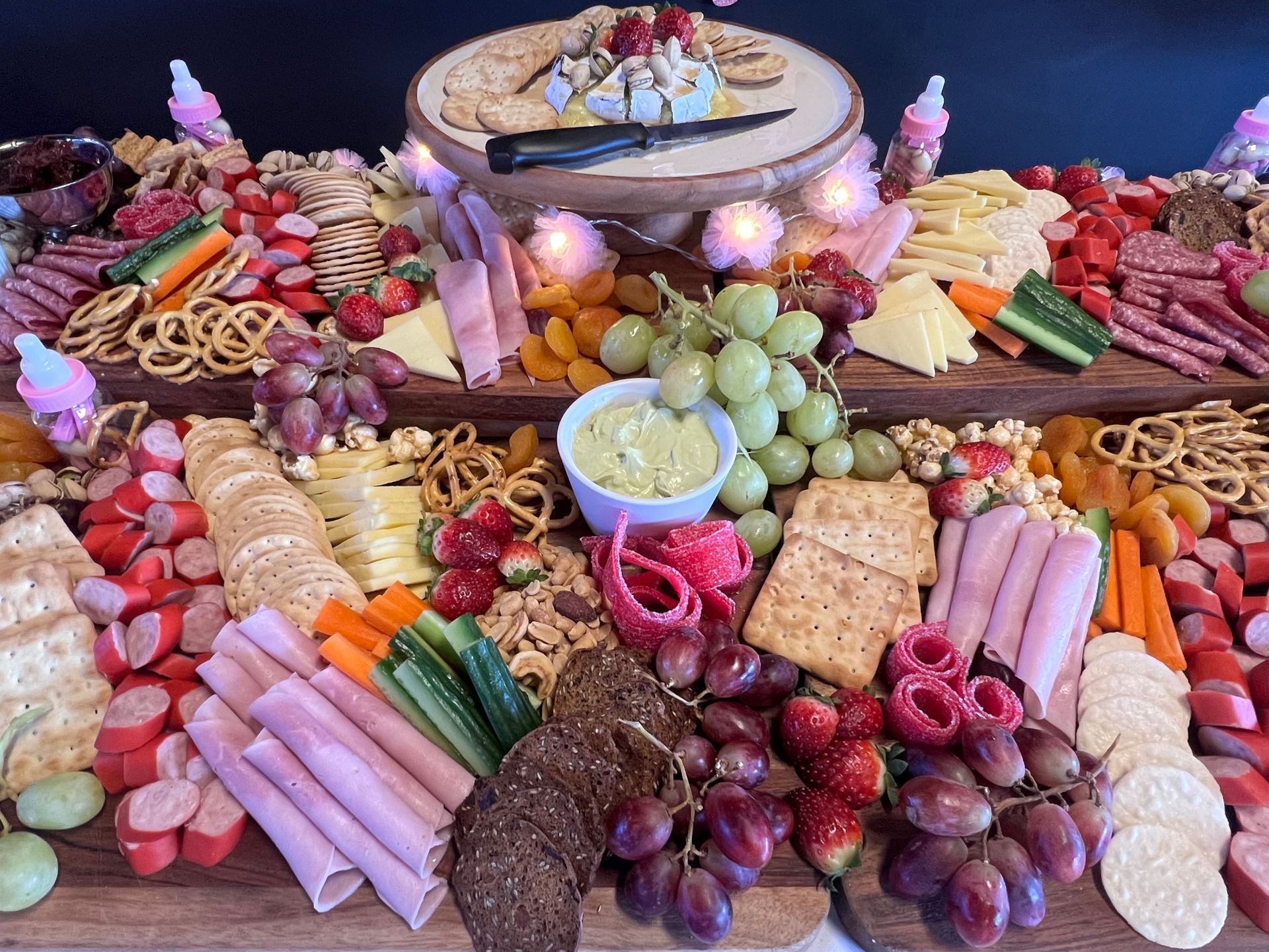 Charcuterie board with cheeses, meats, crackers, fruits, and vegetables.