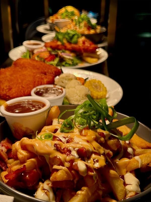 Plates of restaurant food: schnitzel, fries with sauce, salad, vegetables, and more plates stacked.