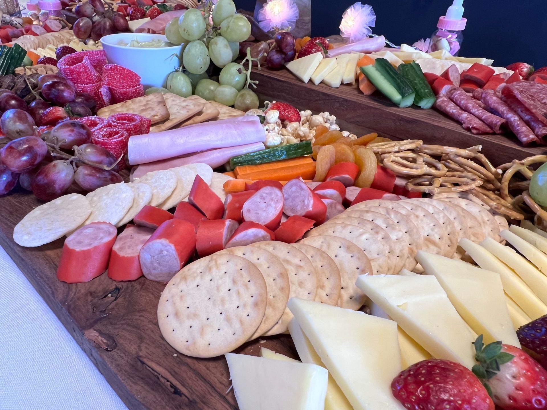 Charcuterie board with various foods, including grapes, crackers, cheese, sausage, and vegetables.