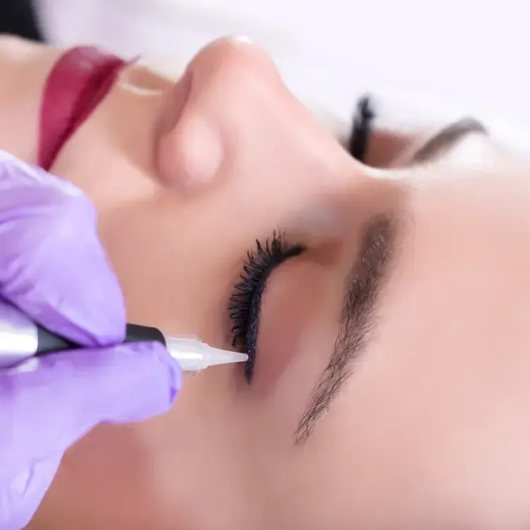 A woman is getting eyeliner tattooed on her eye.