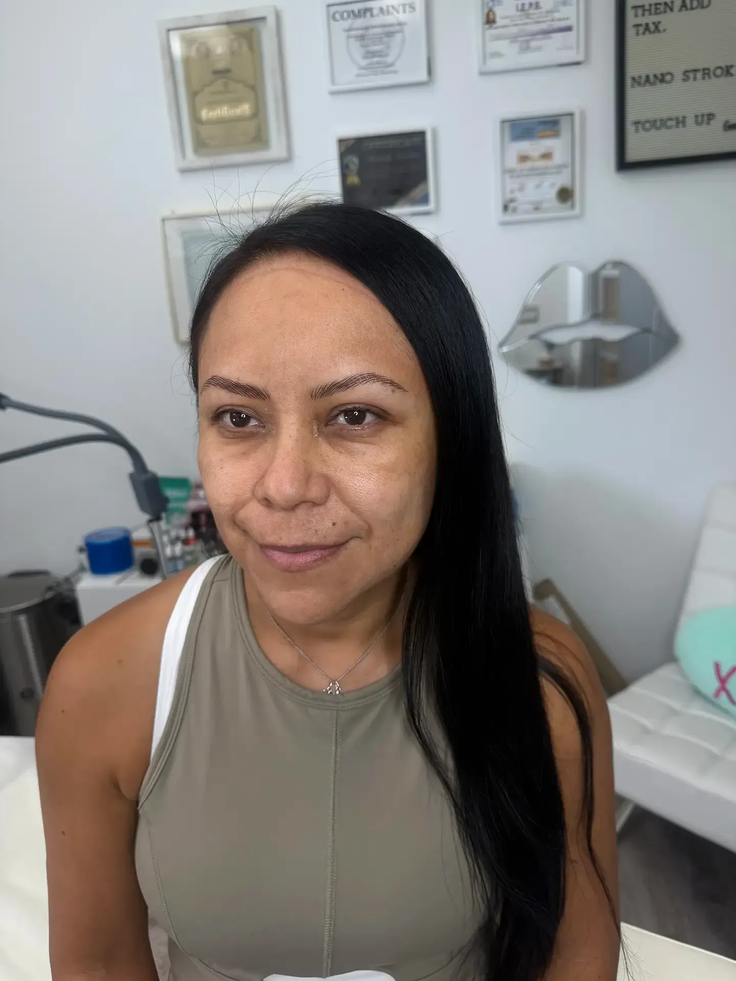 Woman with dark hair and a neutral-toned top poses in a beauty studio. 