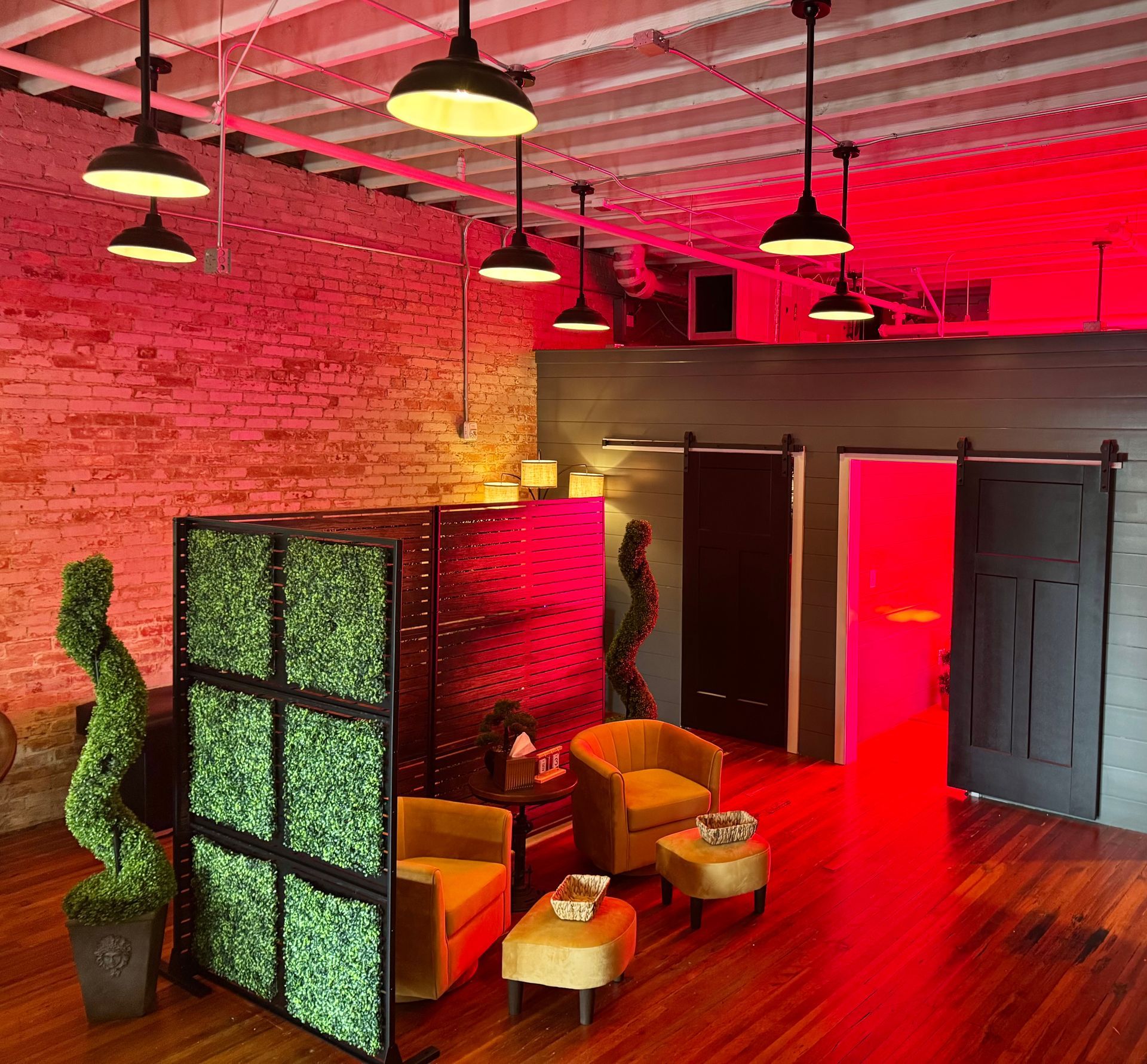 Red-lit spa interior with seating, a green privacy screen, and hanging lights.