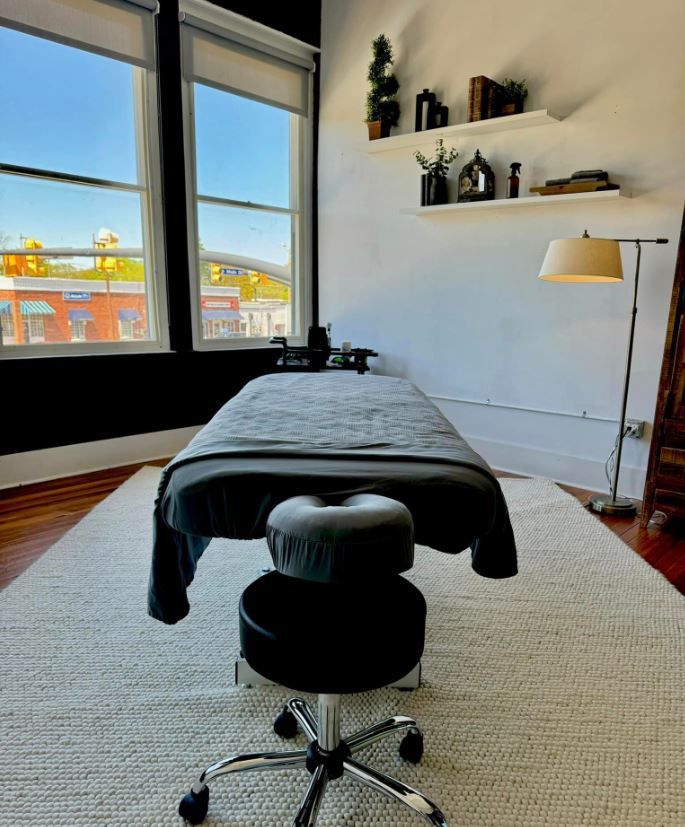 A massage table in a room with a stool and a lamp