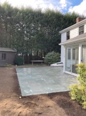 A backyard with a newly installed patio, shed, trees, and a house.