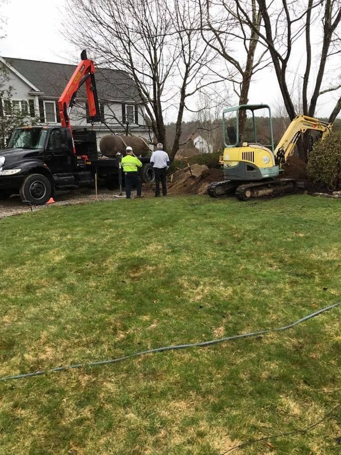Workers near a house with a truck-mounted crane and excavator; digging in the yard.