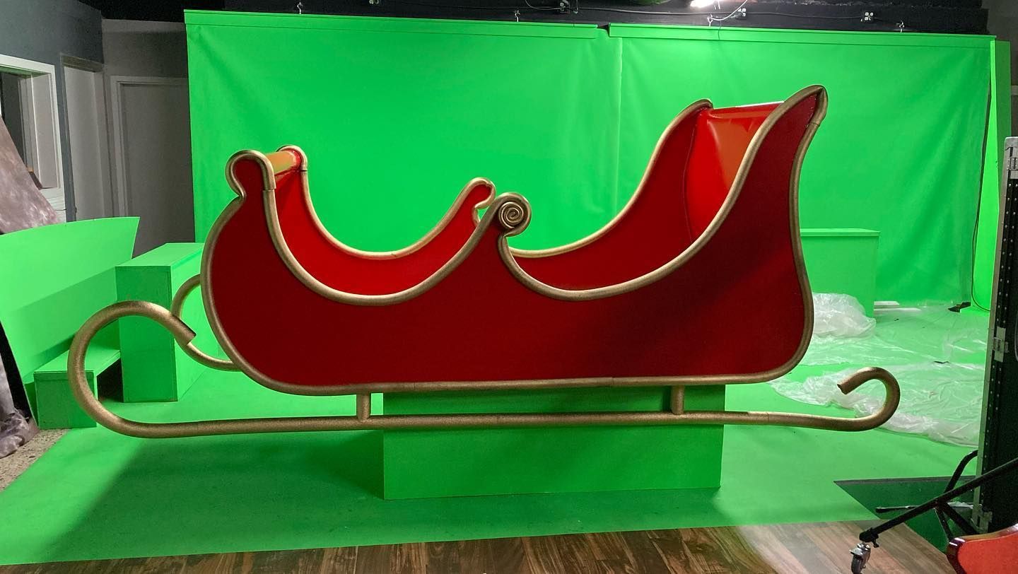 Red sleigh with gold trim on a studio set with green screen backdrop