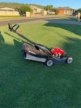A Honda lawn mower is sitting on top of a lush green lawn.