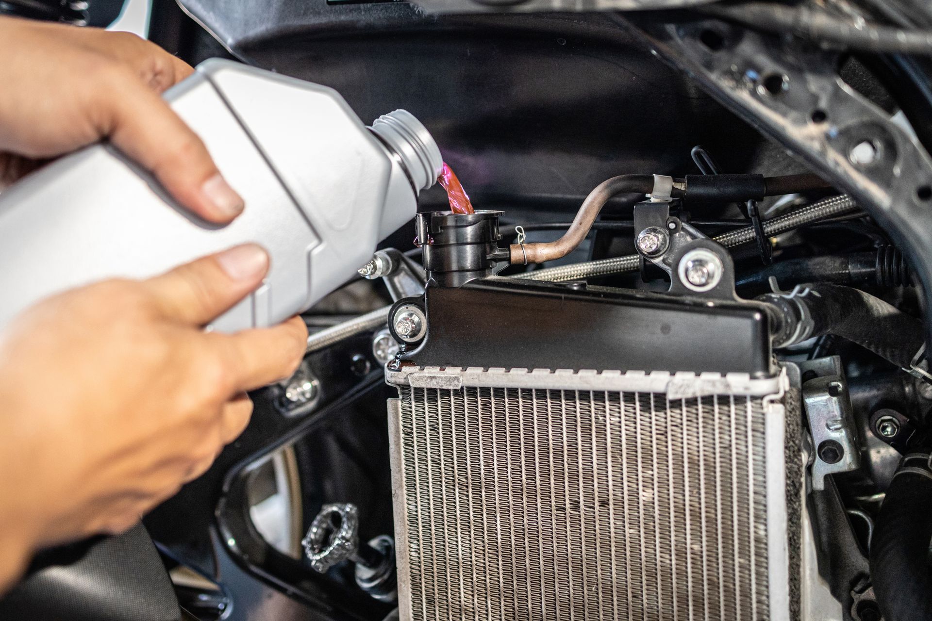Technician pouring coolant into a radiator tank Technician pouring coolant into a radiator tank