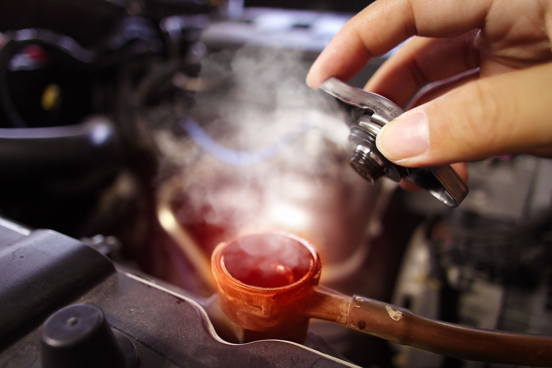 Mechanic opening a steaming radiator cap during an emergency radiator repair service.
