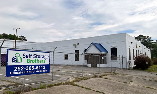 Self Storage Brothers building with blue awning and Self Storage Brothers sign along a fenced lot