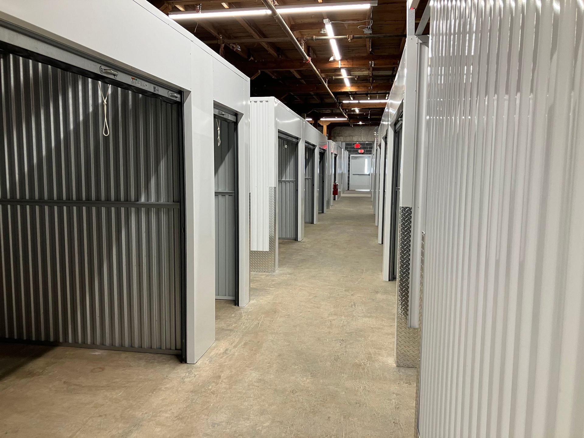 White industrial storage warehouse with loading dock doors and empty parking lot under a clear sky