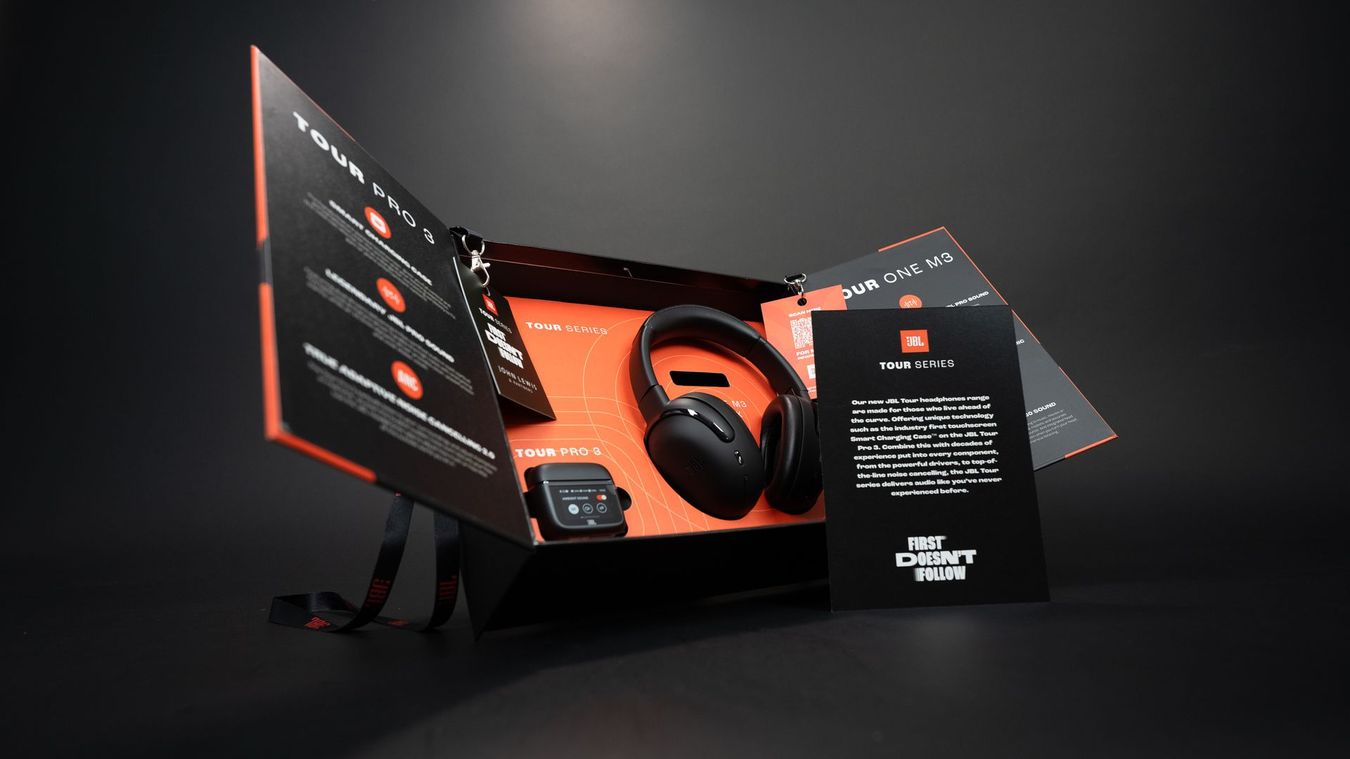 Black and orange gaming headset box and booklet on a dark background, shown in a product display.