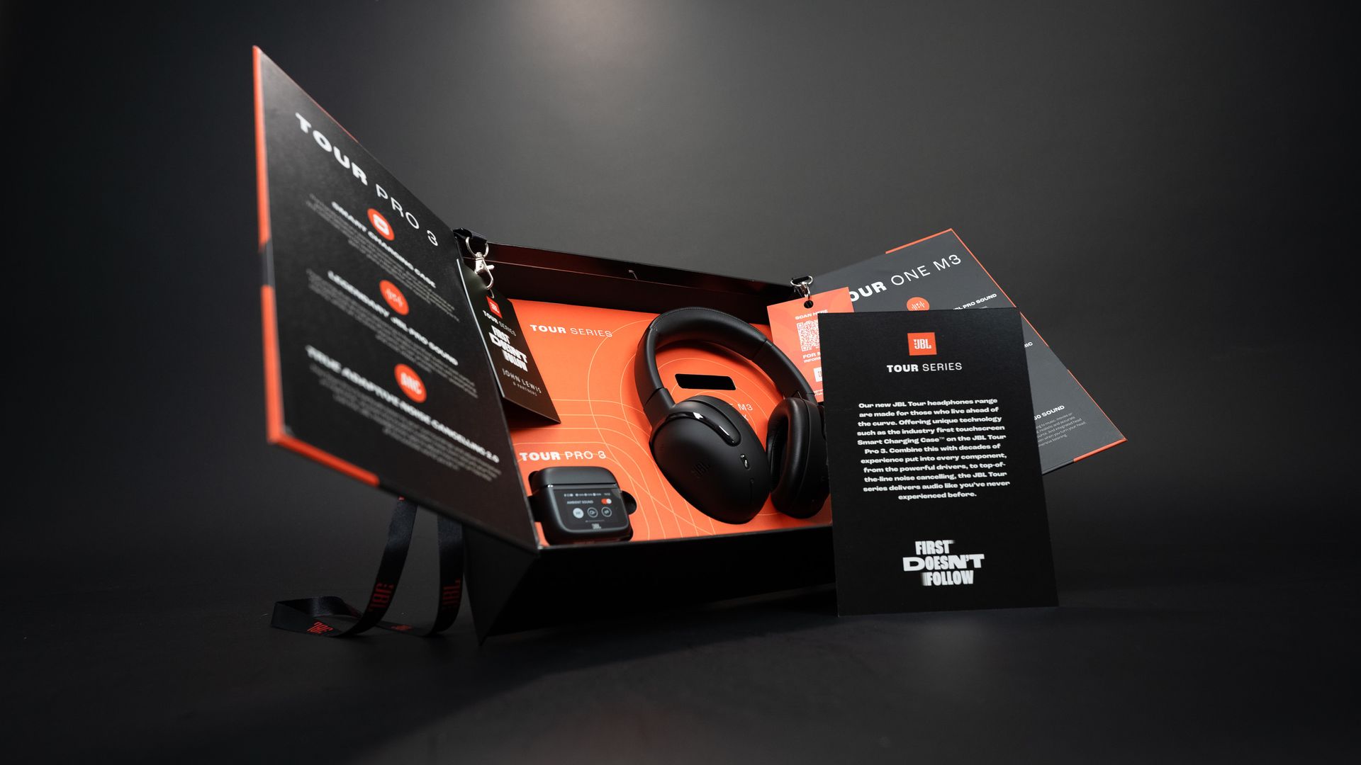 Black and orange gaming headset box and booklet on a dark background, shown in a product display.