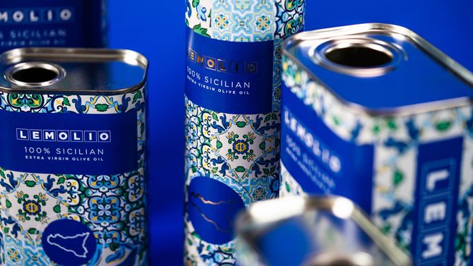 Blue decorated Limonio tin cans with ornate floral patterns and open tops on a blue background