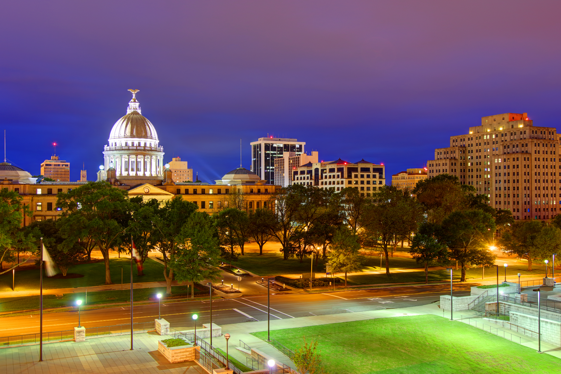 A large building with a dome on top of it is lit up at night.