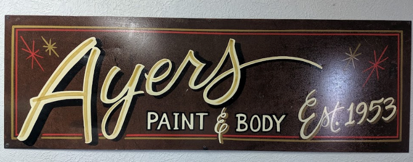 Ayers Paint & Body sign on a dark background with gold script and “Est. 1955”