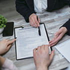 Hands reviewing a home insurance form on a desk with a pen and notebook.