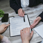 Hands reviewing a home insurance form on a desk with a pen and notebook.