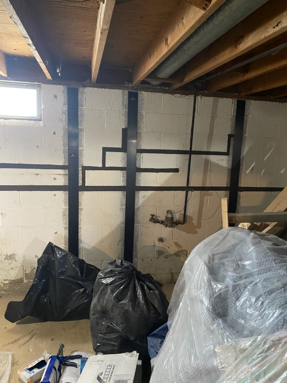 A basement with a lot of trash bags on the floor