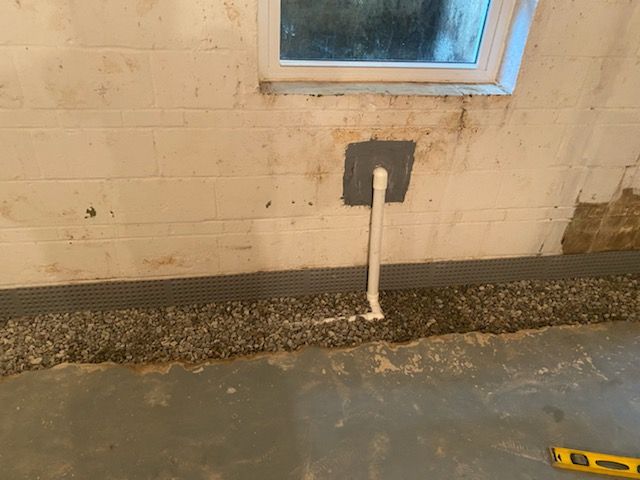 A pipe is being installed in a basement next to a window.