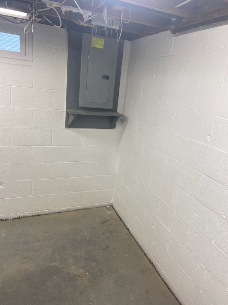 An empty basement with white brick walls and a gray floor.