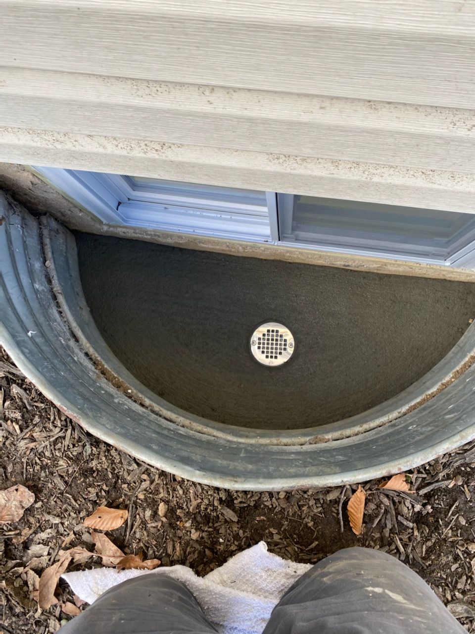 A person is standing in front of a window well.