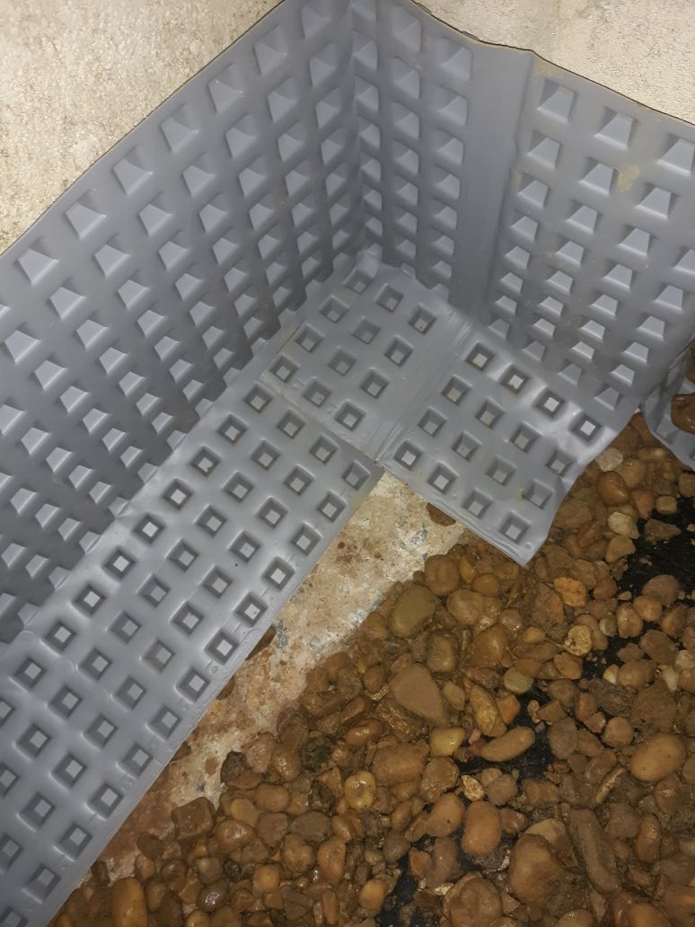 A drainage mat is sitting on top of a pile of rocks.